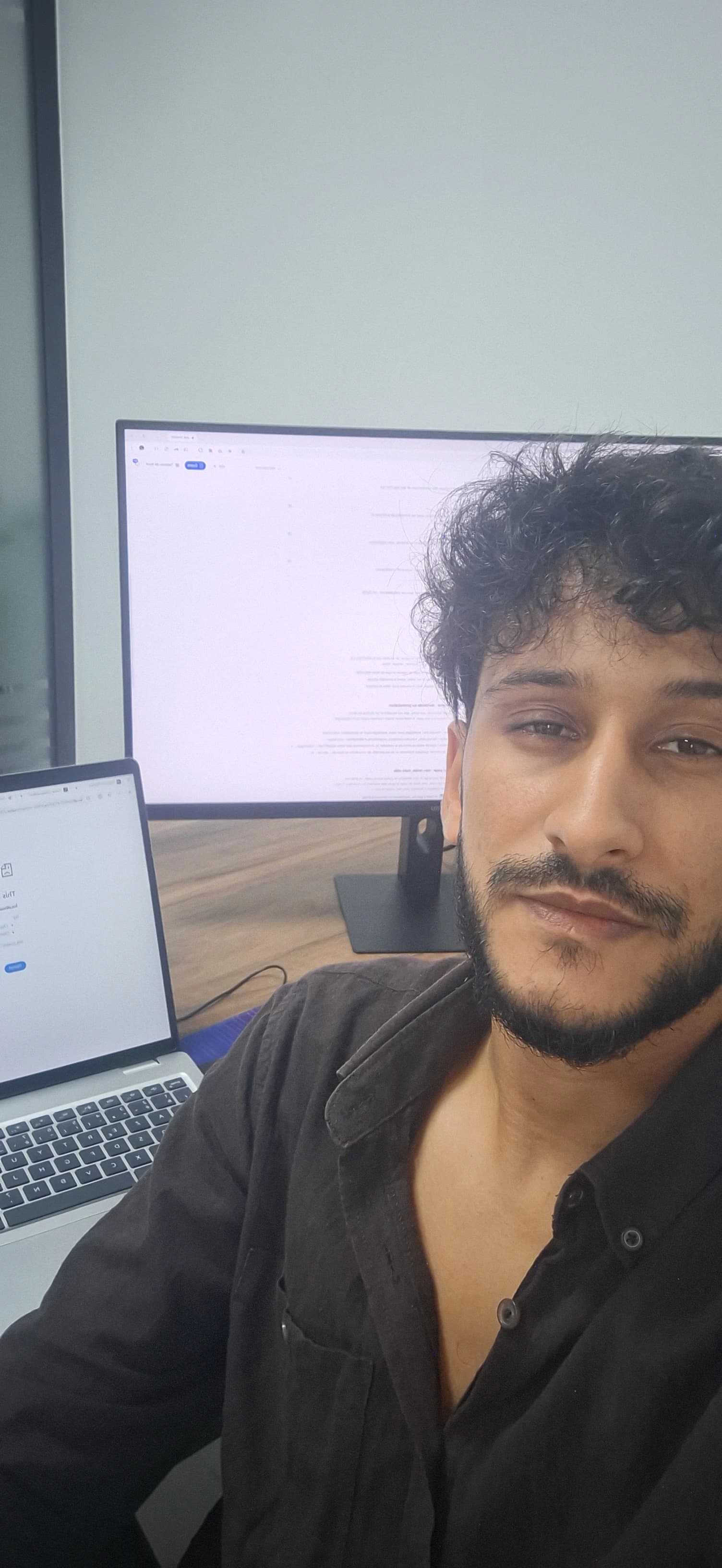 Kamal at his desk, with his laptop and monitor beside him.